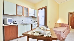 A compact kitchen with white cabinets, a microwave, and a dining area with a table set for two.
