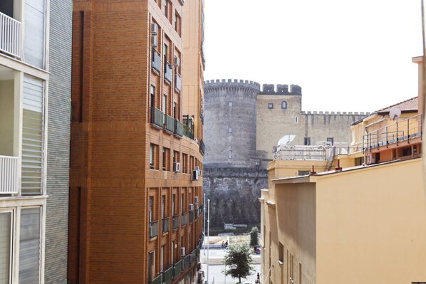 A narrow street with a historic stone tower in the background.