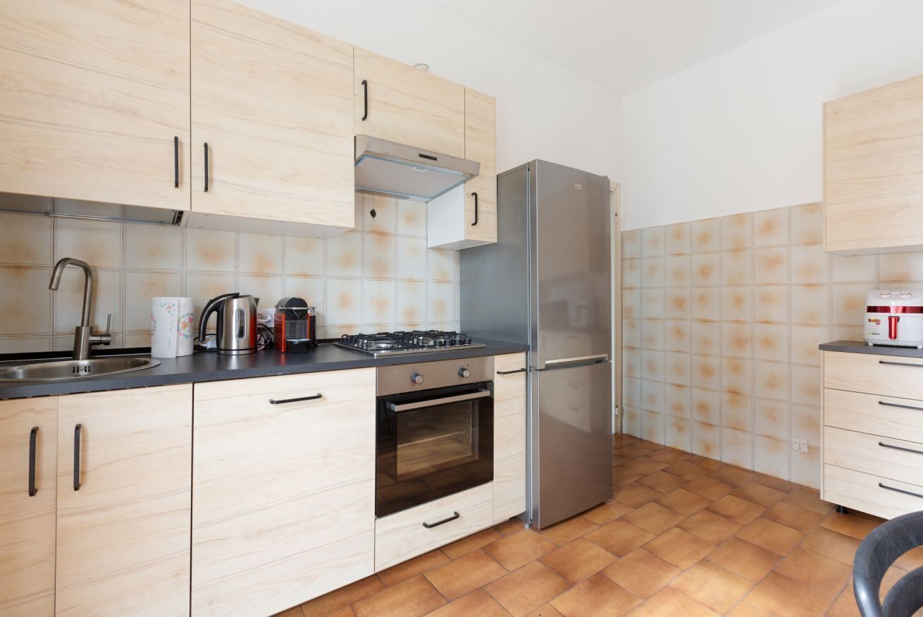 Una cocina con armarios de madera clara, un refrigerador de acero inoxidable, una estufa a gas y un horno empotrado.