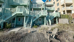 A multi-story building with a wooden deck and outdoor seating area. - Sunkissed Sands @ Perdido Dunes | Spacious & Beachfront | Direct Beach Access | My Beach Getaways (Pensacola)