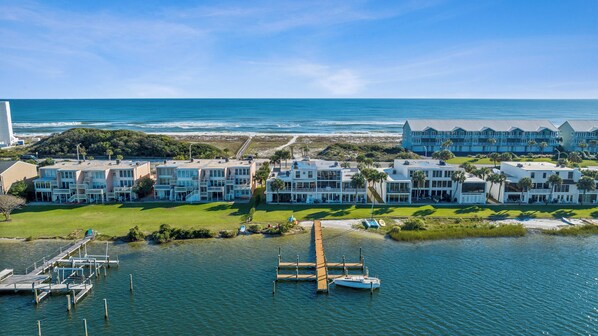 A coastal hotel with multiple buildings, a dock, and a boat.