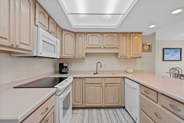 Una cocina moderna con armarios de madera, microondas integrado, estufa y lavavajillas.