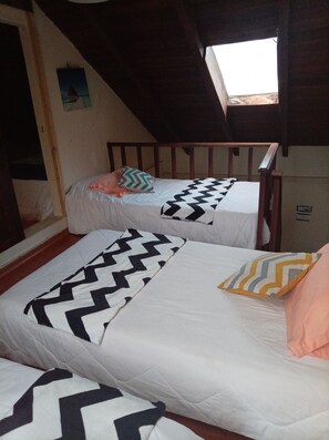 A dormitory room with two beds, each with a patterned bedspread, a small window, and a wooden headboard. - CASA HERMOSA QUITO (Quito)