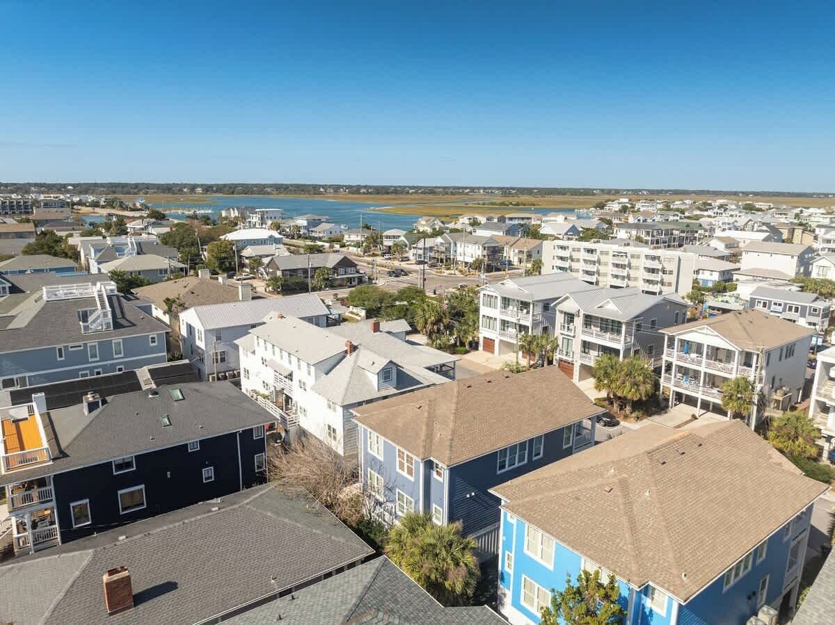 Un área residencial costera con varias casas de dos pisos, algunas con balcones, y una vista despejada del océano.