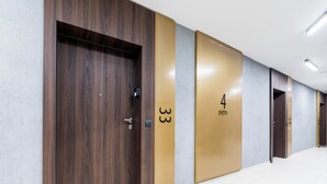 Un pasillo con puertas de madera, puertas numeradas y suelo de baldosas.