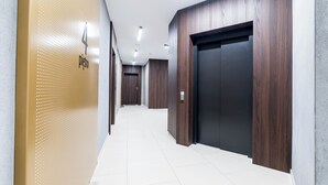 Un pasillo moderno con suelo de baldosas, paneles de madera en las paredes y una puerta con cerradura electrónica.
