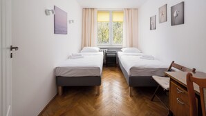Een slaapkamer met twee bedden, een bureau en een stoel.