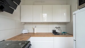 Een kleine keuken met witte kastjes, een gasfornuis, een broodrooster en een spoelbak.