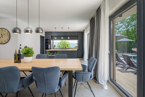 Enjoy meals in the kitchen with a central island and dining area, offering a view of the pool and outdoor furniture.