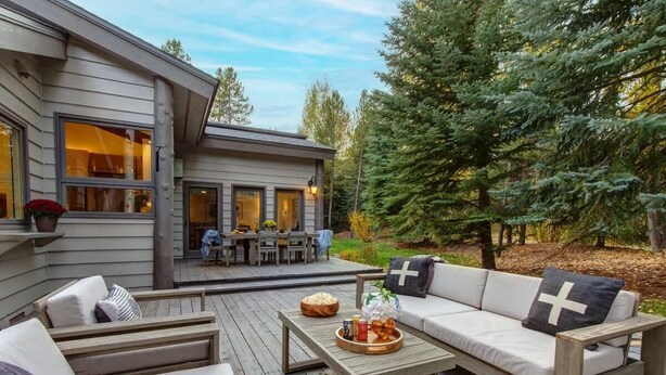 A deck with a sofa, a table, and a dining area with chairs.