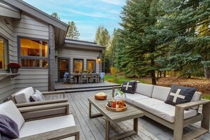 Eine Terrasse mit einer Couch, einem Tisch und einem Essbereich mit Stühlen.