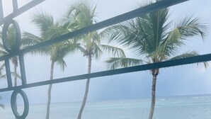 A beach view with palm trees and a railing. - Stunning Caribbean Sea views! (Christiansted)