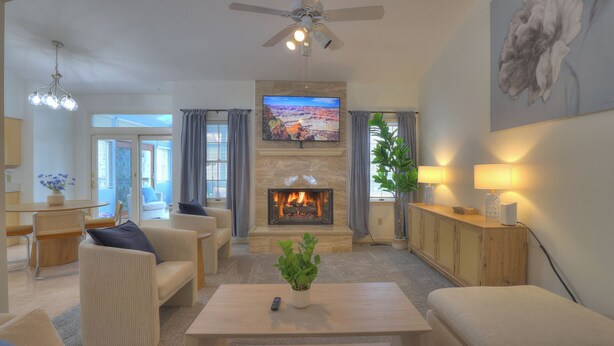 A living room with a fireplace, comfortable seating, a television, and a ceiling fan. - Spacious 5-bedroom House, Hot Tub, Firepit, Game Rooms, Theater Room and More! (Decatur)