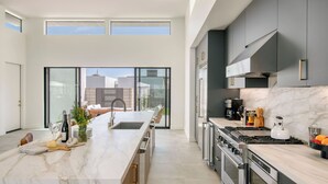 A modern kitchen with a large island, stainless steel appliances, and a view to the outdoors. - The Reserve at Polo Villas by AvantStay (La Quinta)