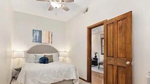 Ein Schlafzimmer mit Bett, Nachttischen, Deckenventilator und Holztür.