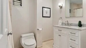 Ein Badezimmer mit Toilette, Waschbecken, Spiegel und einem gerahmten Bild an der Wand.