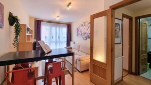 Een kamer met een eettafel, rode stoelen, een bank en een schuifdeur naar een balkon.