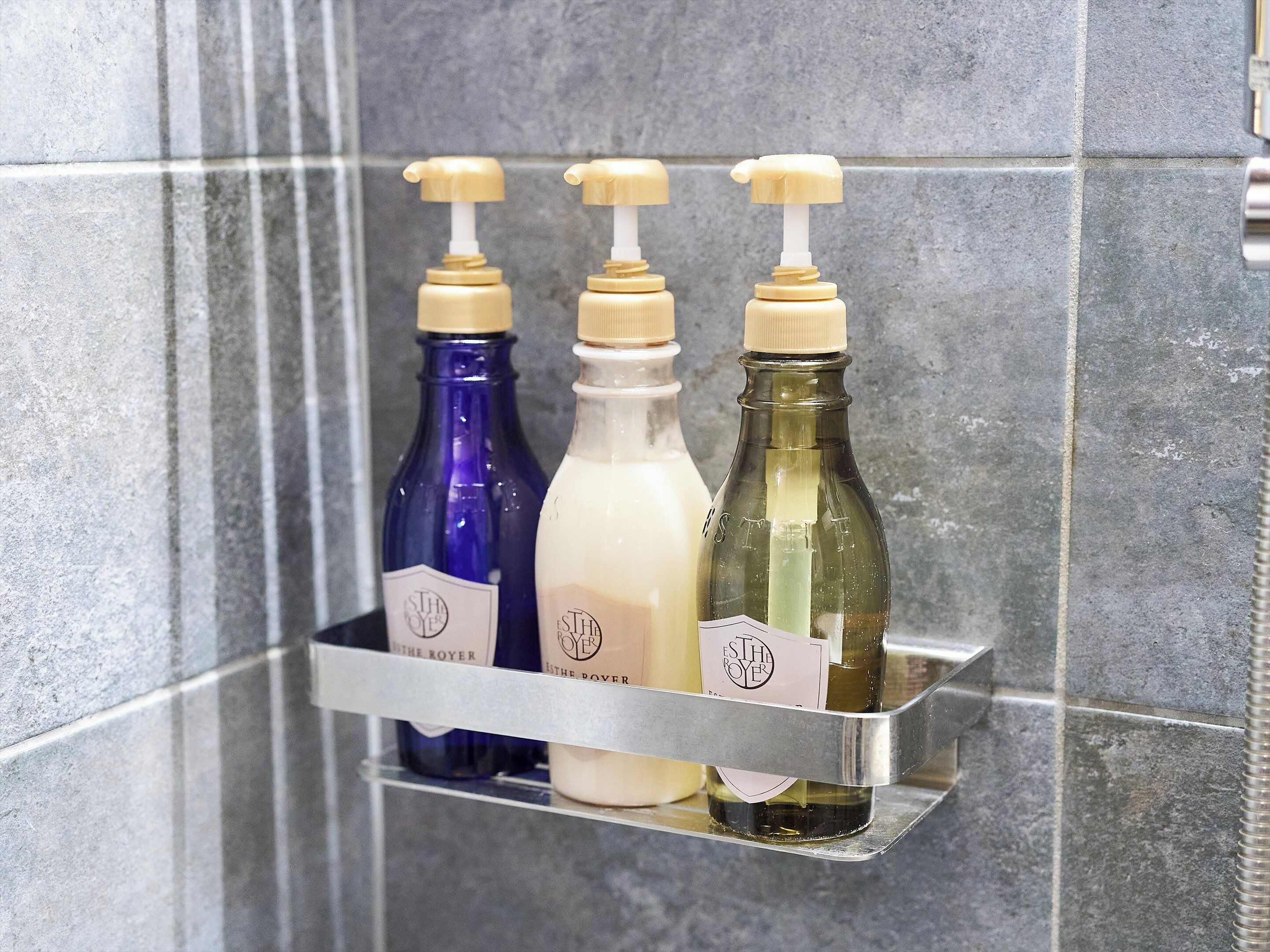 A bathroom shelf with three bottles of liquid soap.
