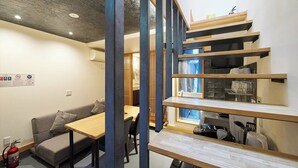 Un intérieur moderne comprenant un escalier, un canapé, une table à manger et des appareils de cuisine.