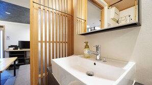 Une salle de bain avec un lavabo blanc, un miroir au-dessus et une cloison en bois.