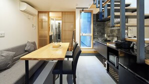 Un espace de vie compact comprenant un coin repas, une kitchenette et une porte coulissante donnant accès à la salle de bain.