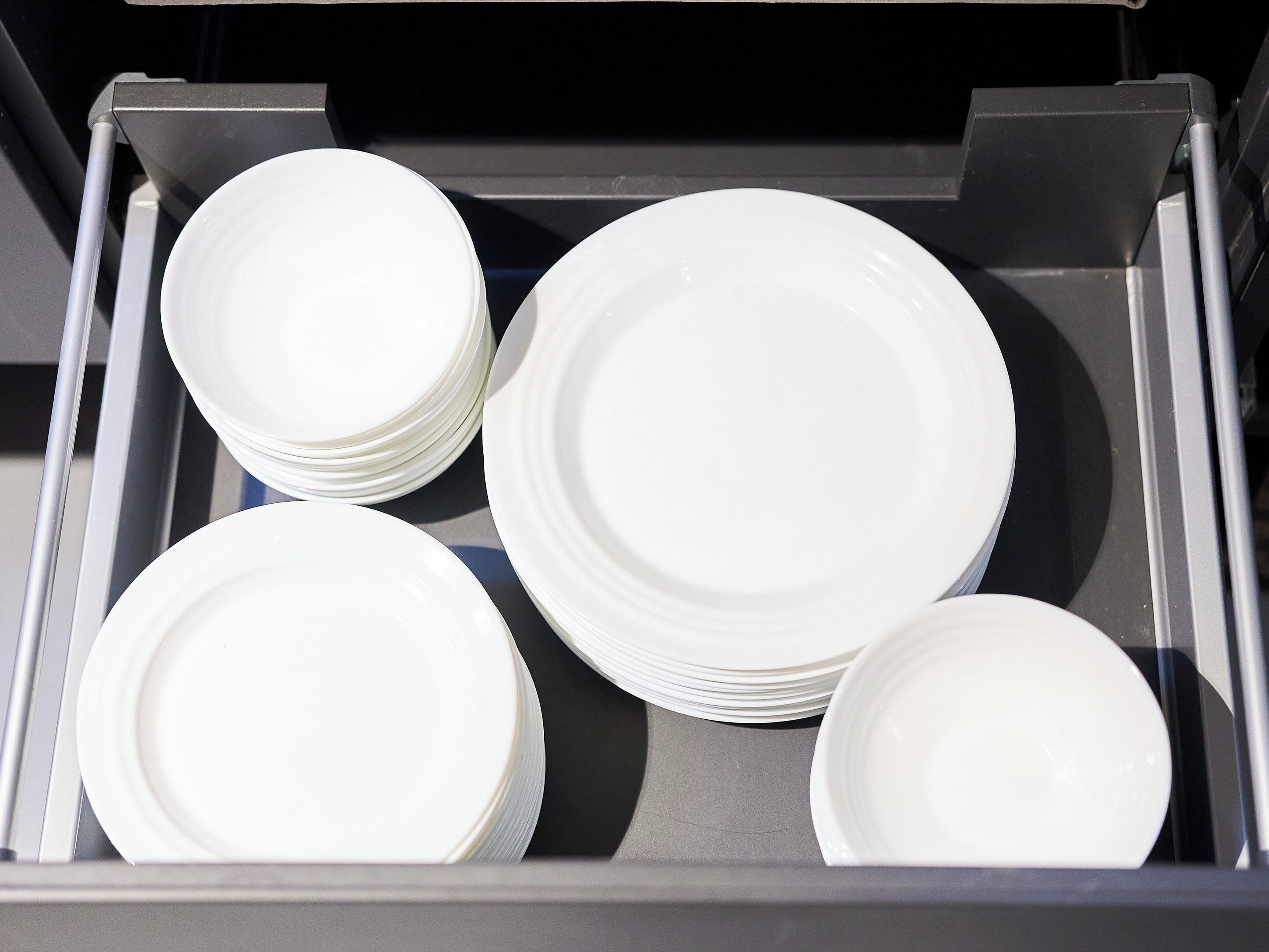 A drawer containing several white plates.
