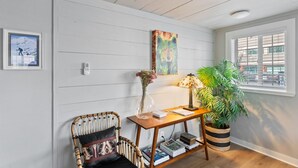 A cozy room with a wooden chair, a small table with a lamp, a potted plant, and a framed picture on the wall. - Stylish Downtown Cottage, Walk Everywhere (Bend)