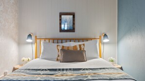 A neatly made bed with a patterned bedspread, two bedside lamps, and a framed picture on the wall. - Stylish Downtown Cottage, Walk Everywhere (Bend)