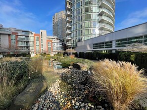 A modern building with a reflective water feature surrounded by diverse vegetation. - Downtown Vancouver with False Creek View, across from Rogers Arena & BC Place (Vancouver)