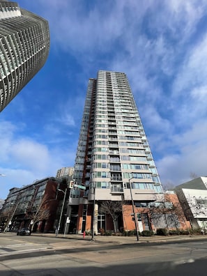 A tall, modern building with a curved facade, multiple balconies, and a clear sky. - Downtown Vancouver with False Creek View, across from Rogers Arena & BC Place (Vancouver)