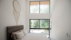 Une chambre avec un grand lit, une fenêtre et un objet décoratif fixé au mur.