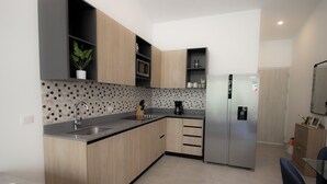Une cuisine moderne avec des meubles en bois, un réfrigérateur en acier inoxydable et un four à micro-ondes.