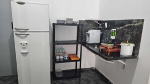 Una cocina compacta con un refrigerador blanco, un estante negro, un tostador y un salpicadero de mármol.