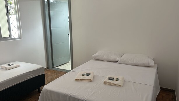 Habitación de hotel con cama, una cama o sofá adicional, y puerta de vidrio corredera que da a un espacio al aire libre.