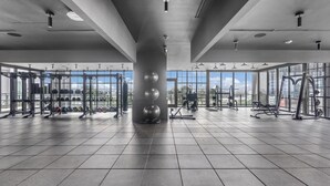Ein geräumiges Fitnessstudio mit unterschiedlichen Trainingsgeräten, großen Fenstern und modernem Design.