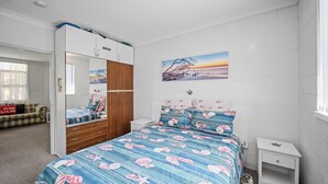 A bedroom with a bed, a wardrobe, a nightstand, and a painting on the wall. - Forster Lodge 16: 1  BR, 1  BA Apartment in Forster, Sleeps 4 (Forster)