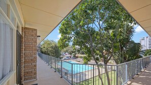 A balcony with a view of a swimming pool, surrounded by trees and a parking lot. - Forster Lodge 16: 1  BR, 1  BA Apartment in Forster, Sleeps 4 (Forster)