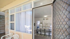 A room with a large window, a dining area with chairs, a kitchen with cabinets, and a stone wall. - Forster Lodge 16: 1  BR, 1  BA Apartment in Forster, Sleeps 4 (Forster)