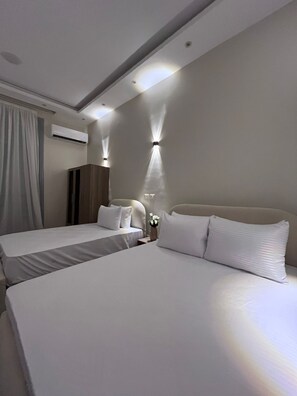 Ein Hotelzimmer mit zwei Betten, einem Kleiderschrank, einer Klimaanlage und Wandleuchten.