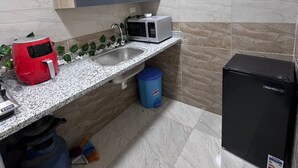 Une cuisine compacte équipée d’un four à micro-ondes, d’un grille-pain et d’un réfrigérateur.