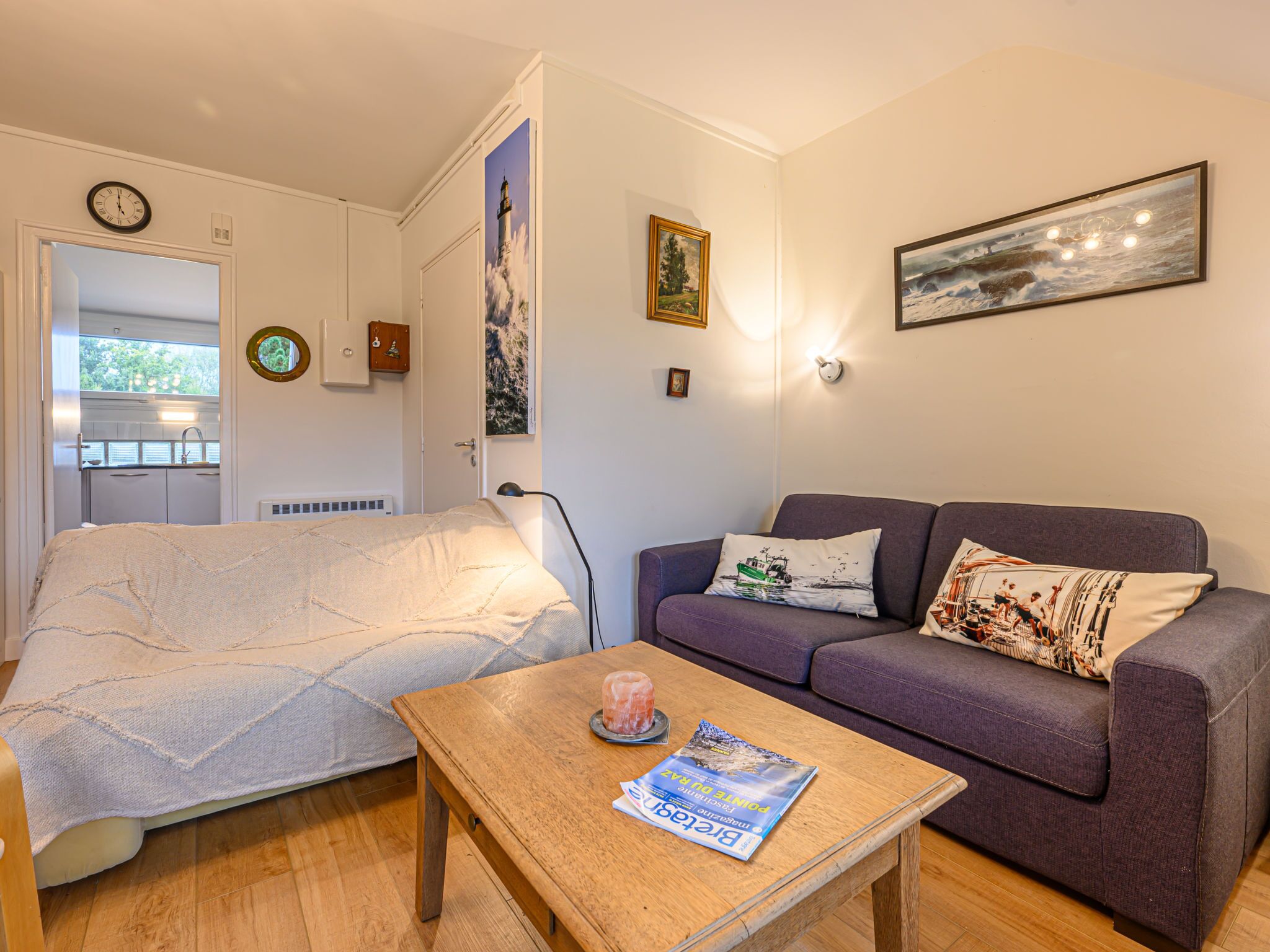 Ein gemütliches Wohnzimmer mit einem Bett, einem Sofa, einem Holztisch und einer Zeitschrift.