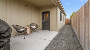 A covered patio area with two chairs, a small table with a plant, and a door leading to the house. - 3 bedroom, 2 bath with fire pit and game room (Kennewick)