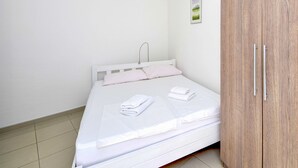 A bedroom with a bed, white walls, a wooden wardrobe, and a small framed picture on the wall. - Jasmina by Interhome (Blace)
