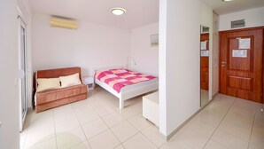 Ein Schlafzimmer mit einem Bett, einer braunen Couch, einem kleinen Tisch und einem Holzschrank.