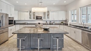 A modern kitchen with a large island, stainless steel appliances, and a pendant light. - Heart of Cocoa Beach, Rooftop Deck, Hammock & Private Balcony (Cocoa Beach)