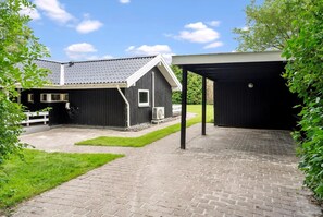 A black barn with a white window and a covered area with a black roof. - Summer house close to nature and beach (Dronningmølle)