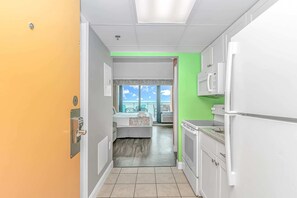 A hotel room with a balcony, a kitchenette, and a bathroom.