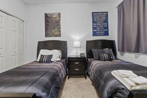 A bedroom with two beds, a nightstand, a lamp, and two motivational posters on the wall. - River Oaks 48-D (Myrtle Beach)