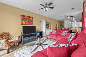 Ein Wohnzimmer mit Fernseher, rotem Sofa und Deckenventilator.