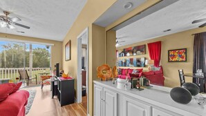 A spacious living area with a kitchen counter, a red sofa, and a dining area with a table and chairs. - River Oaks 48-D (Myrtle Beach)